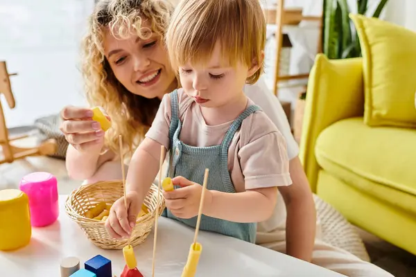 Una mamma dai capelli ricci e sua figlia bambina imparano creativamente con la pasta secca usando il metodo Montessori a casa. — Foto stock