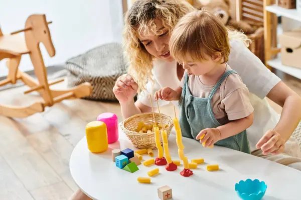 A curly mother and her toddler daughter engage in Montessori play, exploring toys and learning together at home. — Stock Photo