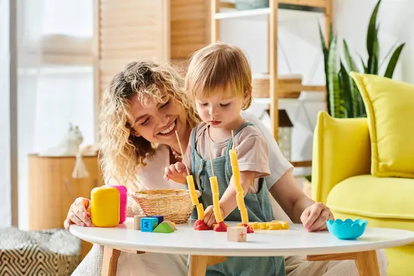Une mère bouclée et sa fille tout-petit profitent du temps de jeu Montessori avec une variété de jouets à la maison. — Photo de stock