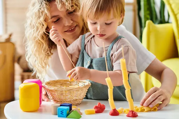 Una madre dai capelli ricci e sua figlia minore interagiscono scherzosamente con i giocattoli educativi Montessori a casa.. — Foto stock