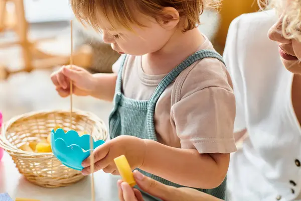 A little girl stands in front of a basket, exploring its contents with curiosity and wonder. — Stock Photo