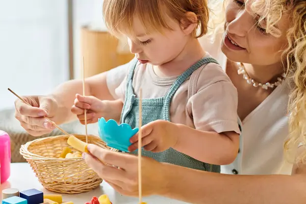 A curly mother and her toddler daughter are happily playing with educational toys using the Montessori method at home. — Stock Photo