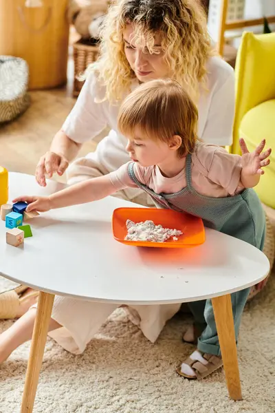 A curly-haired mother engages her toddler daughter in playful learning using the Montessori method at home. — Stock Photo