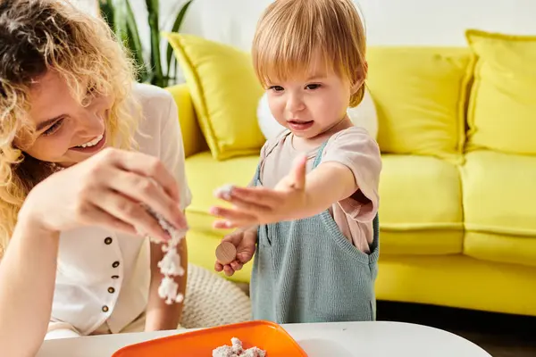 Una madre rizada y su hija pequeña exploran juguetonamente y experimentan con varios alimentos utilizando el método de educación Montessori en casa. - foto de stock