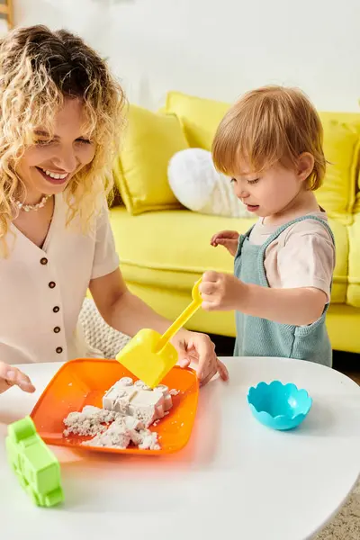 Eine Mutter mit lockigem Haar und ihre kleine Tochter spielen zu Hause mit Montessori-Spielzeug und betreiben praktisches Lernen und Erforschen. — Stockfoto