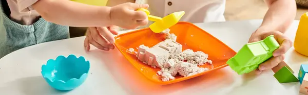 Kleinkind-Mädchen erkundet und spielt mit einem Plastikbehälter voller Lebensmittel in Montessori-inspirierter Lernumgebung zu Hause. — Stockfoto