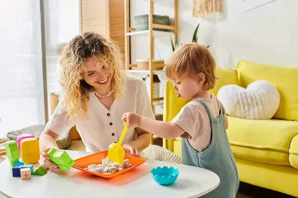 Eine Mutter mit lockigem Haar und ihre kleine Tochter spielen zu Hause fröhlich mit Montessori-Lernspielzeug. — Stockfoto