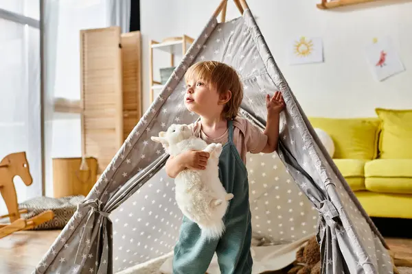 Toddler girl cuddling a stuffed animal inside a teepee, creating a magical and imaginative playtime setting at home. — Stock Photo