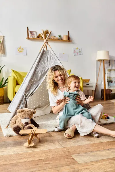 A curly mother and her toddler daughter engage in Montessori learning, sitting together on the floor in a harmonious moment. — Stock Photo