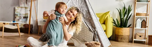 A curly mother and her toddler daughter engage in imaginative play inside a teepee — Stock Photo