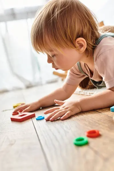 A young child engrossed in playing with toys on the floor, exploring creativity and learning. — Stock Photo