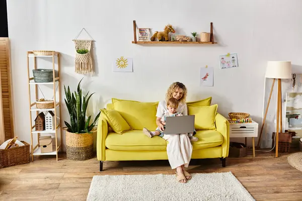 Ragazza riccia bambino sul divano giallo, assorbito nell'utilizzo del computer portatile a casa. — Foto stock