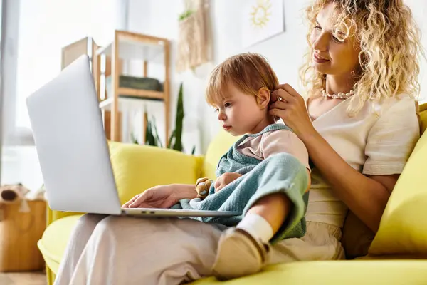 A curly mother sits on a couch with her toddler daughter on her lap in a heartwarming moment of bonding at home. — Stock Photo