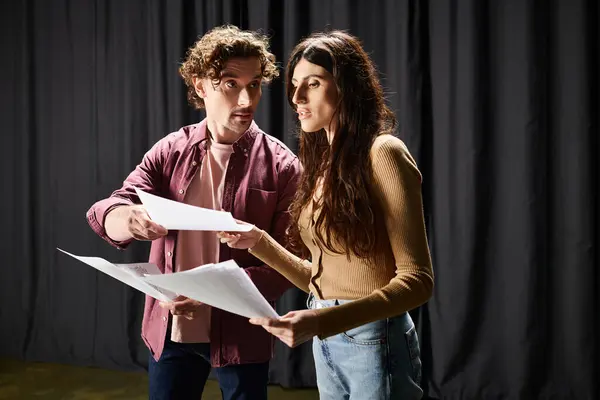 A man and woman stand elegantly in front of a black curtain during theater rehearsals. — Stock Photo