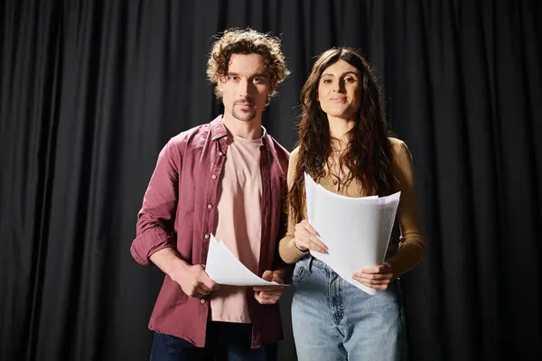 Un hombre guapo está junto a una mujer sosteniendo una hoja de papel durante los ensayos en el teatro.. - foto de stock