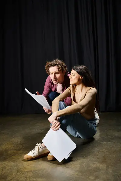 Ein gut aussehender Mann und eine gut aussehende Frau sitzen bei Theaterproben eng am Boden. — Stockfoto