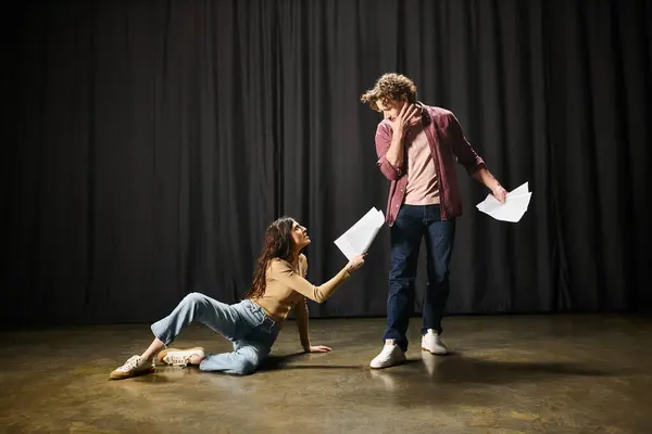 Мужчина стоит на коленях рядом с женщиной на земле во время театральных репетиций. — стоковое фото