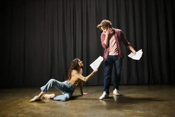 A man kneels next to a woman on the ground during theater rehearsals. — Stock Photo