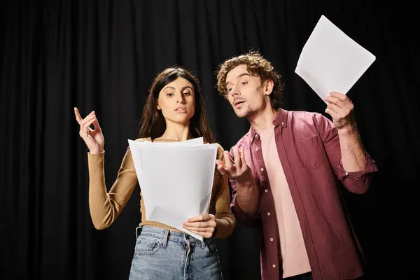 A handsome man and a woman rehearsing together, holding a sheet of paper. — Stock Photo