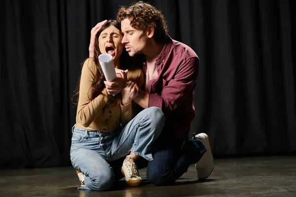 Мужчина стоит на коленях рядом с женщиной, выступая во время репетиции театра. — стоковое фото