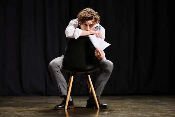 Ein Mann sitzt selbstbewusst auf einem Stuhl und hält einen Zettel in der Hand. — Stockfoto