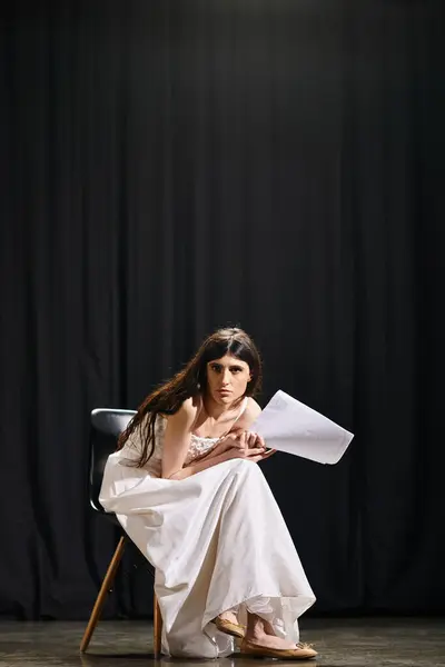 Une femme étonnante dans une robe blanche fluide assise gracieusement sur une chaise. — Photo de stock
