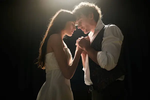 A man and a woman gracefully dance in the dimly lit theater. — Stock Photo