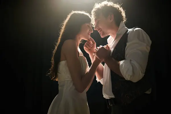 Homme et femme élégants dansent gracieusement ensemble dans un cadre de faible luminosité. — Photo de stock