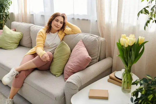 Middle aged woman sitting elegantly on a gray couch. — Stock Photo