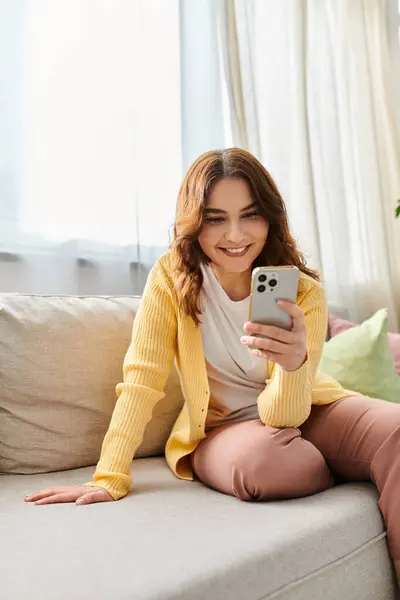 Middle aged woman enjoying a calm moment on a couch, engaged with her cell phone. — Stock Photo