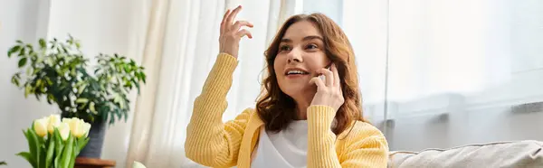 Middle-aged woman sitting on couch, engrossed in phone call. — Stock Photo