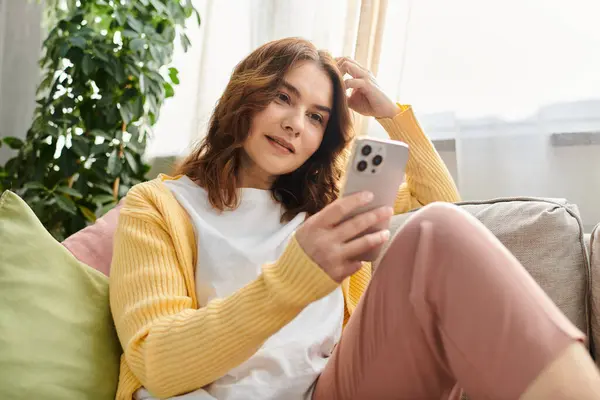 Frau mittleren Alters in Handy vertieft, während sie sich auf Couch entspannen. — Stockfoto