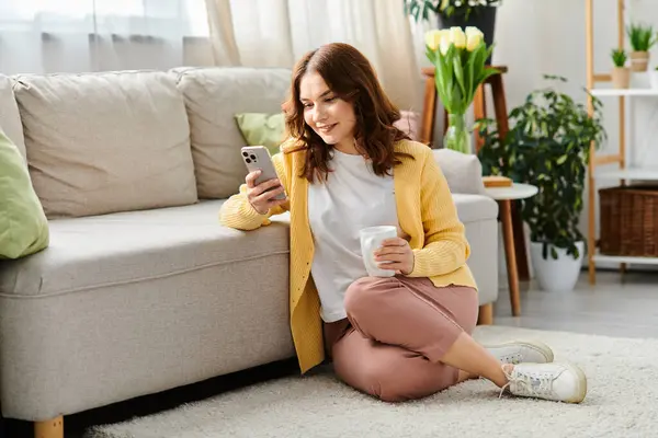 Middle aged woman sits on floor, deeply focused on cell phone. — Stock Photo