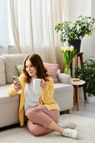 Middle-aged woman sits on floor, savoring a cup of coffee. — Stock Photo