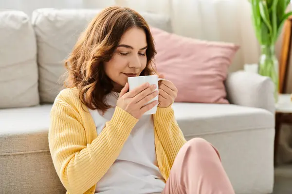 Frau mittleren Alters genießt einen Moment mit Kaffee auf einer gemütlichen Couch. — Stockfoto