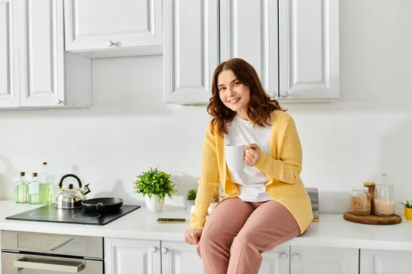 Une femme d'âge moyen assise gracieusement sur un comptoir de cuisine. — Photo de stock