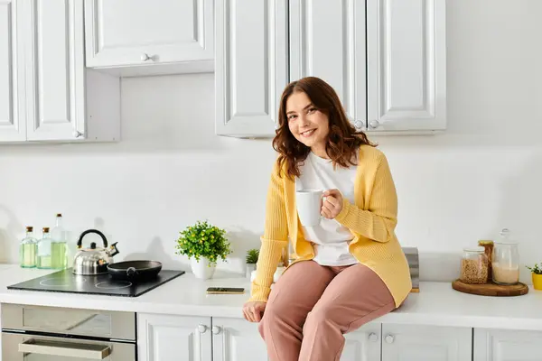 A middle aged woman sitting gracefully on a kitchen counter. — Stock Photo