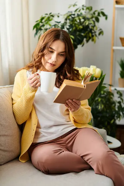 Femme d'âge moyen se détend sur le canapé avec tasse de café. — Photo de stock