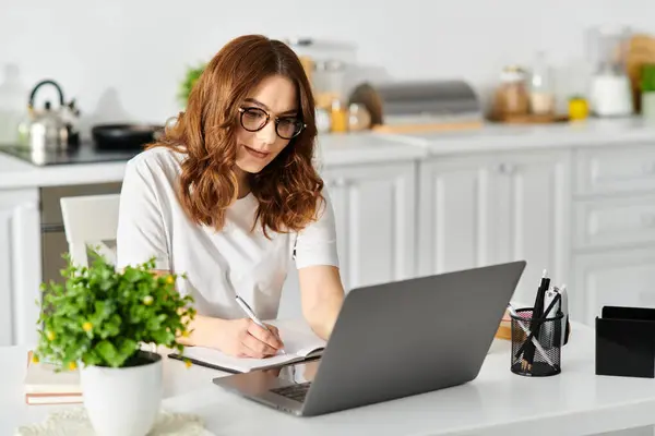 Middle-aged woman engrossed in laptop work at home table. — Stock Photo