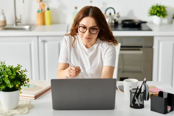 A middle-aged woman engrossed in work on her laptop at a cozy table. — Stock Photo
