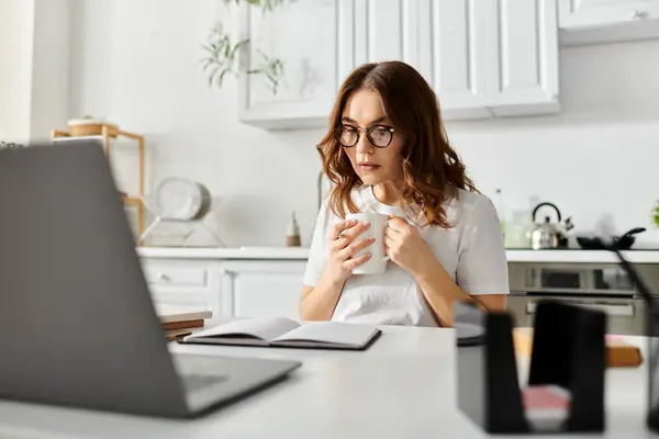 Middle-aged woman immersed in work on laptop at home table. — Stock Photo