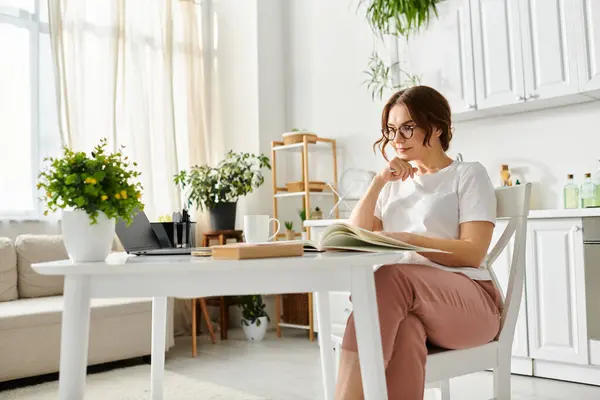 Middle aged woman deeply engrossed in a book while sitting at a table. — Stock Photo