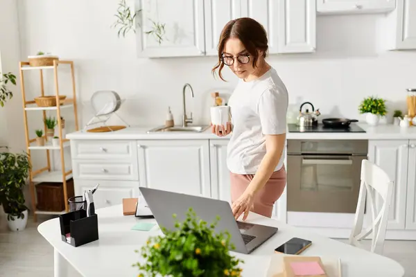 Frau mittleren Alters benutzt Laptop am Küchentisch. — Stockfoto