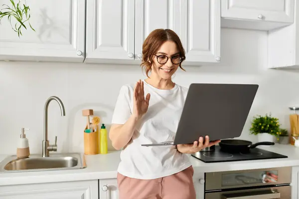 Mujer de mediana edad de pie delante de la computadora portátil - foto de stock