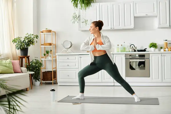 Mujer de mediana edad en pose de yoga, con camisa blanca y polainas. - foto de stock
