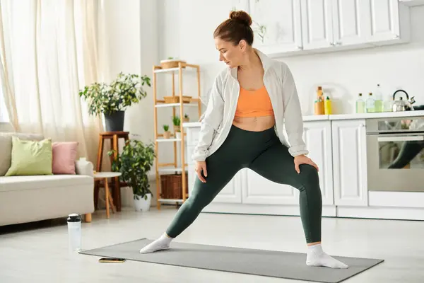 Красивая женщина средних лет в спортивном лифчике и леггинсах стоит на коврике для йоги. — стоковое фото