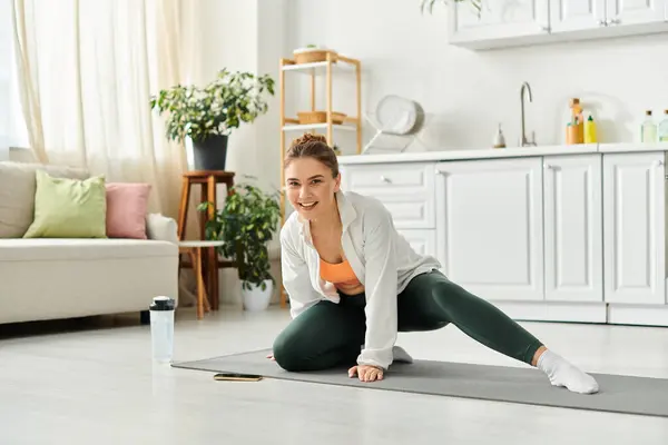 Femme d'âge moyen en chemise blanche pratiquant gracieusement le yoga à la maison. — Photo de stock