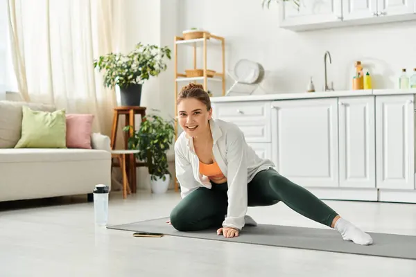 Middle-aged woman in white shirt gracefully practicing yoga at home. — Stock Photo