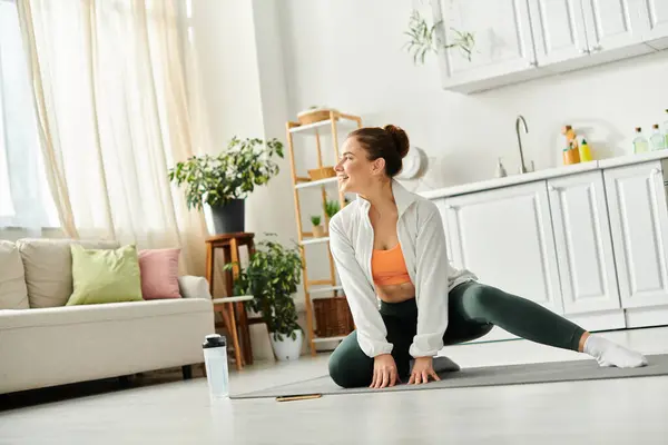 A middle-aged woman gracefully executes a yoga pose in her cozy living room. — Stock Photo