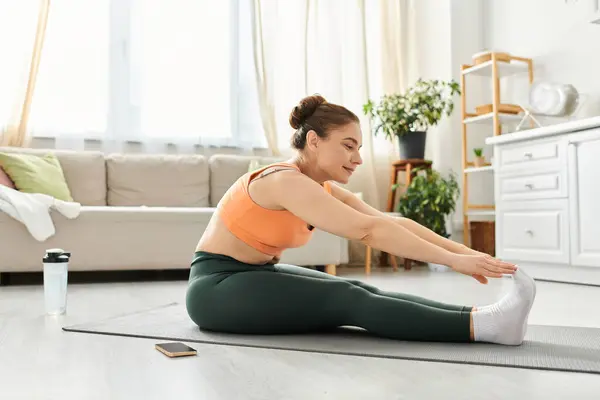 Middle-aged woman gracefully performing a yoga pose in a cozy living room. — Stock Photo